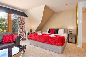 A modern bedroom with a large bed, a sofa, and a dining table. - Finest Retreats - Bryncoch Retreat (Bryncoch)
