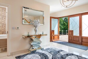 A modern interior with a glass console table, a decorative vase, a large mirror, and a patterned rug.