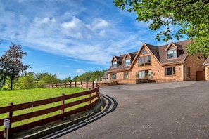 A two-story brick house with a paved driveway and a wooden fence. - Bryncoch Retreat (Bryncoch)