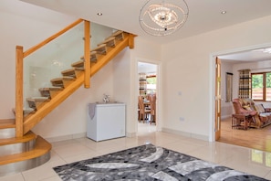 A modern interior with a wooden staircase, a central white refrigerator, and a patterned rug. - Bryncoch Retreat (Bryncoch)