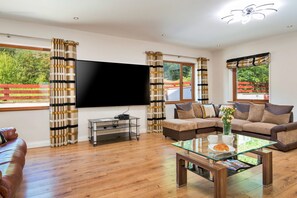 A living room with a flat-screen TV, a glass coffee table, and a sofa with cushions. - Bryncoch Retreat (Bryncoch)