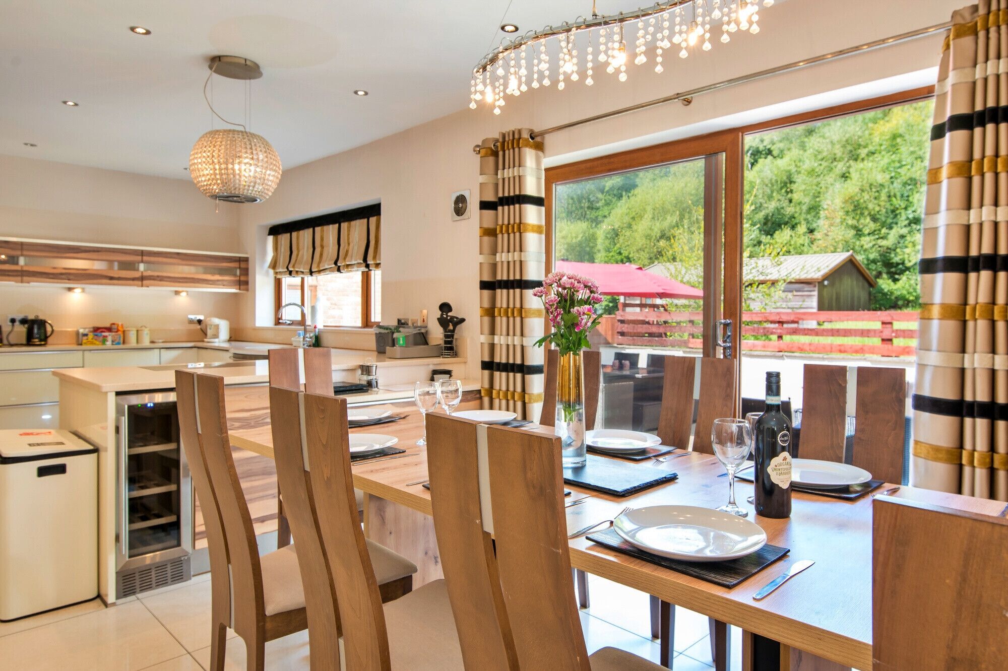 Una cocina moderna con comedor, muebles de madera y vistas al exterior.