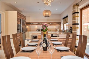 Un comedor con una mesa de madera dispuesta para seis personas, un jarrón de flores y una botella de vino.