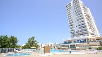 Un hotel de gran altura con área de piscina, varios balcones y cielo despejado.