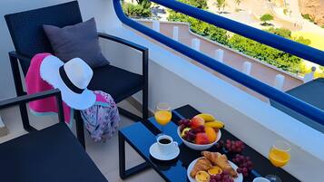 Un balcón con una mesa dispuesta para el desayuno, incluyendo cruasanes, fruta y bebidas.