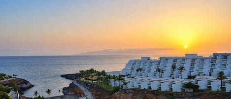 Un hotel frente al mar con vistas al océano, edificios blancos y palmeras.
