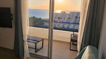 Una habitación con vistas al mar y edificios al atardecer.