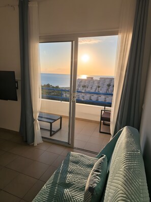Una habitación con vistas al mar y edificios al atardecer.