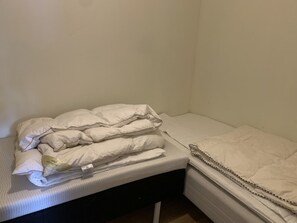Ein kleines Zimmer mit einem Einzelbett, einer weißen Matratze, einer weißen Daunendecke und einer weißen Decke.