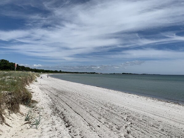 A beach with a sandy shore and a calm sea under a partly cloudy sky.