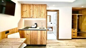 A modern kitchen with wooden cabinetry, a built-in sink, and a dining area with a bench. - Cesa Planber Apartments Mountain View (Canazei)