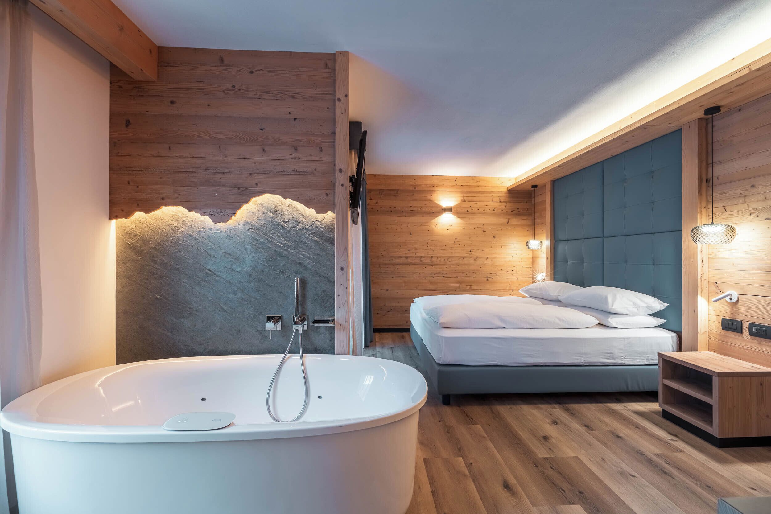 Un baño moderno con una bañera independiente, ducha y cama con cabecero.