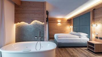 Un baño moderno con una bañera independiente, ducha y cama con cabecero.