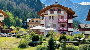 A multi-story building with balconies, surrounded by greenery and mountains. - Cesa Planber Apartments Mountain View (Canazei)