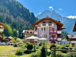 A multi-story building with balconies, surrounded by greenery and mountains. - Cesa Planber Apartments Mountain View (Canazei)