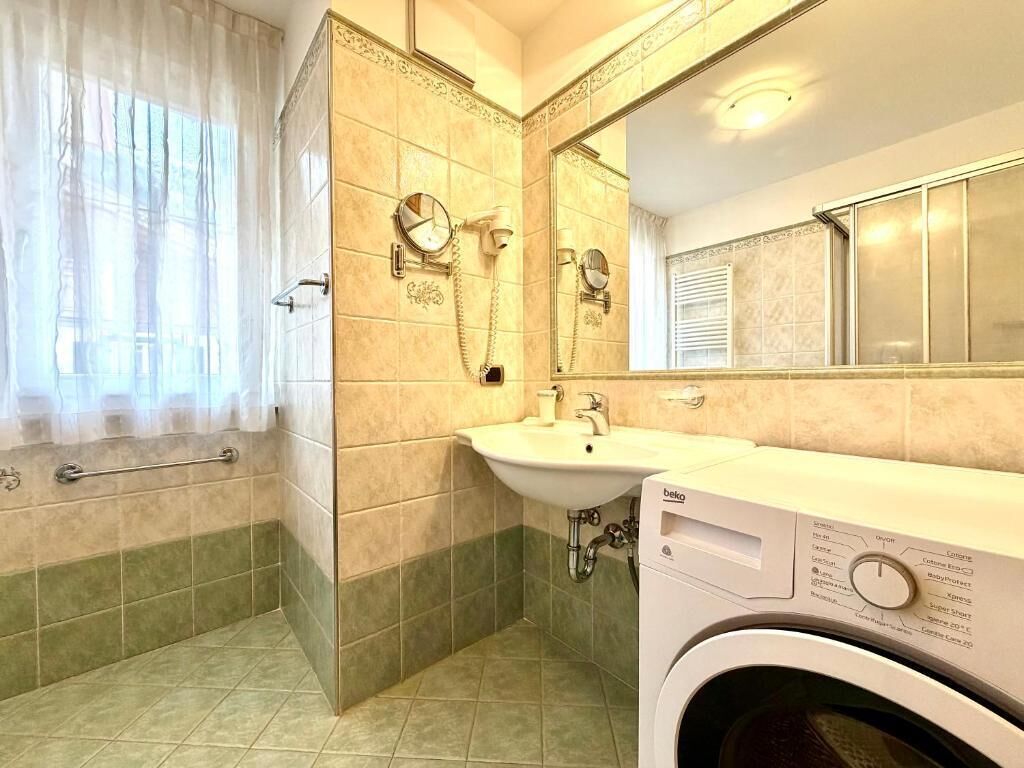Un bagno con vasca, lavandino, specchio e lavatrice.