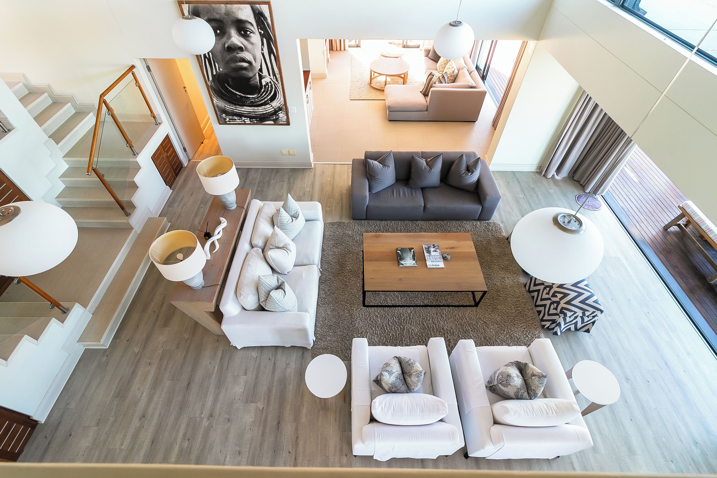 Ein großzügiger Wohnbereich mit Treppe, einem grauen Sofa, einem weißen Sofa und einem Couchtisch.