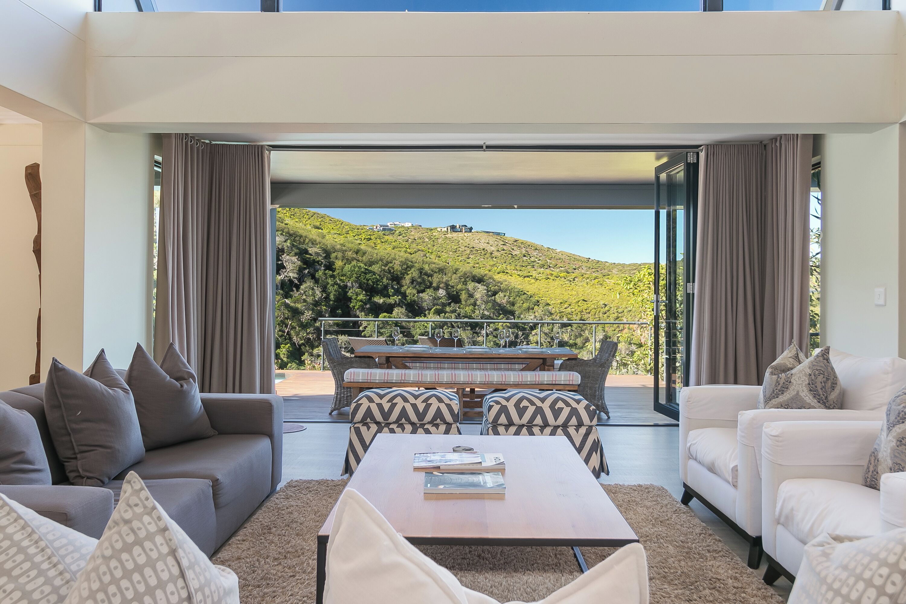 Una sala de estar moderna con un sofá, una mesa de centro y vistas a un balcón con mobiliario exterior.