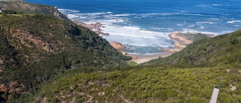 Paisagem costeira com um caminho pavimentado que leva a uma praia.