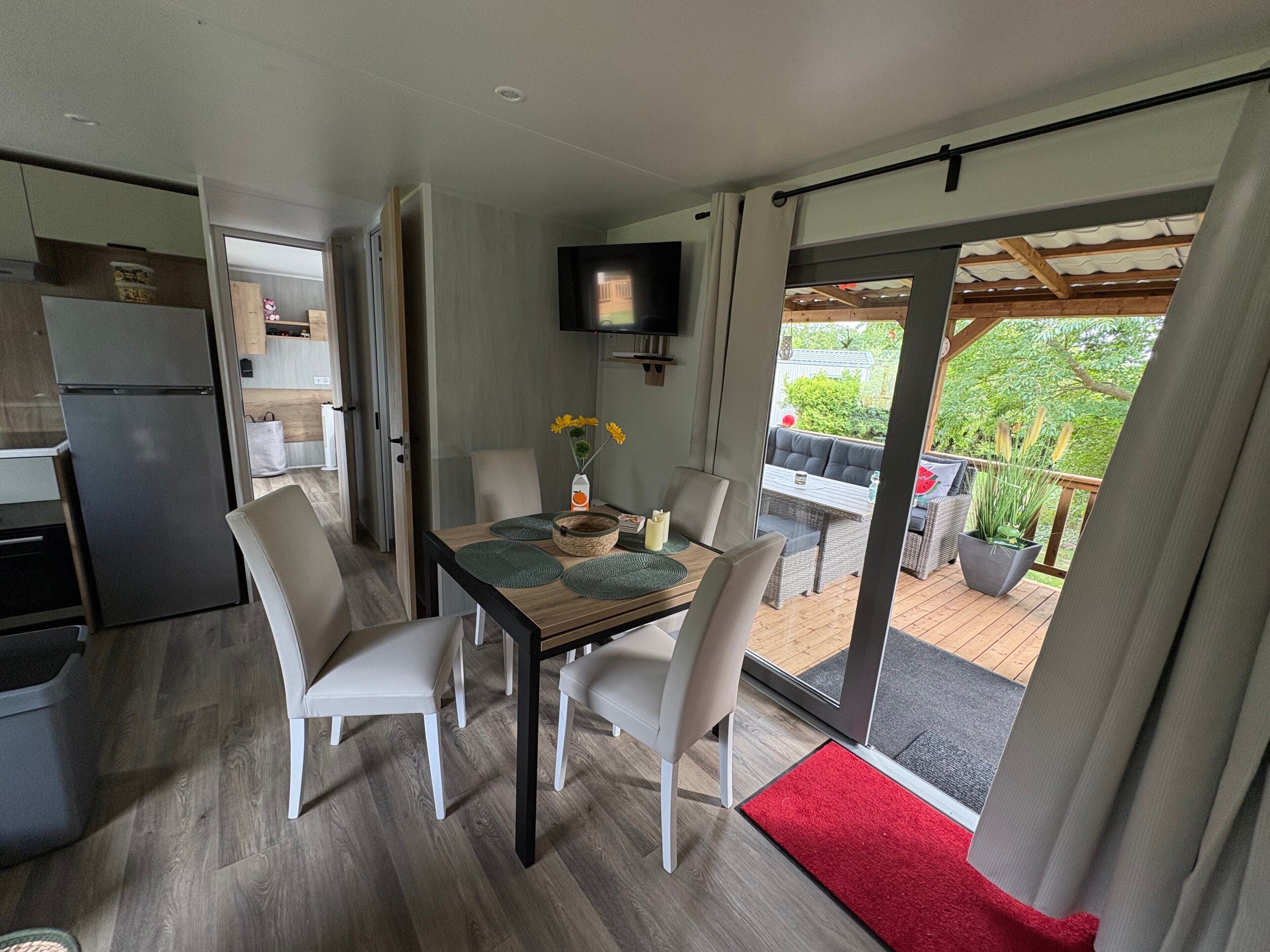 Eine moderne Küche mit integriertem Kühlschrank, ein Essbereich mit Tisch und Stühlen sowie Blick auf die Terrasse.