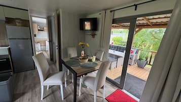 Een moderne keuken met een ingebouwde koelkast, een eethoek met tafel en stoelen, en uitzicht op het buitendek.