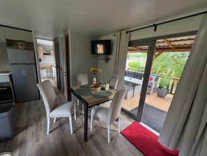 A modern kitchen with a built-in refrigerator, a dining area with a table and chairs, and a view of the outdoor deck.