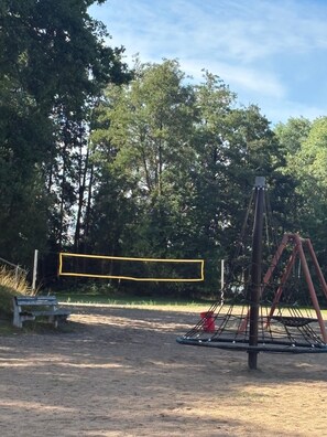 Une aire de jeux avec des balançoires et une zone délimitée par un filet jaune.