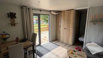 Ein modernes Wohnzimmer mit Essbereich, Holzboden, einer Couch, einem Couchtisch und Blick ins Freie.