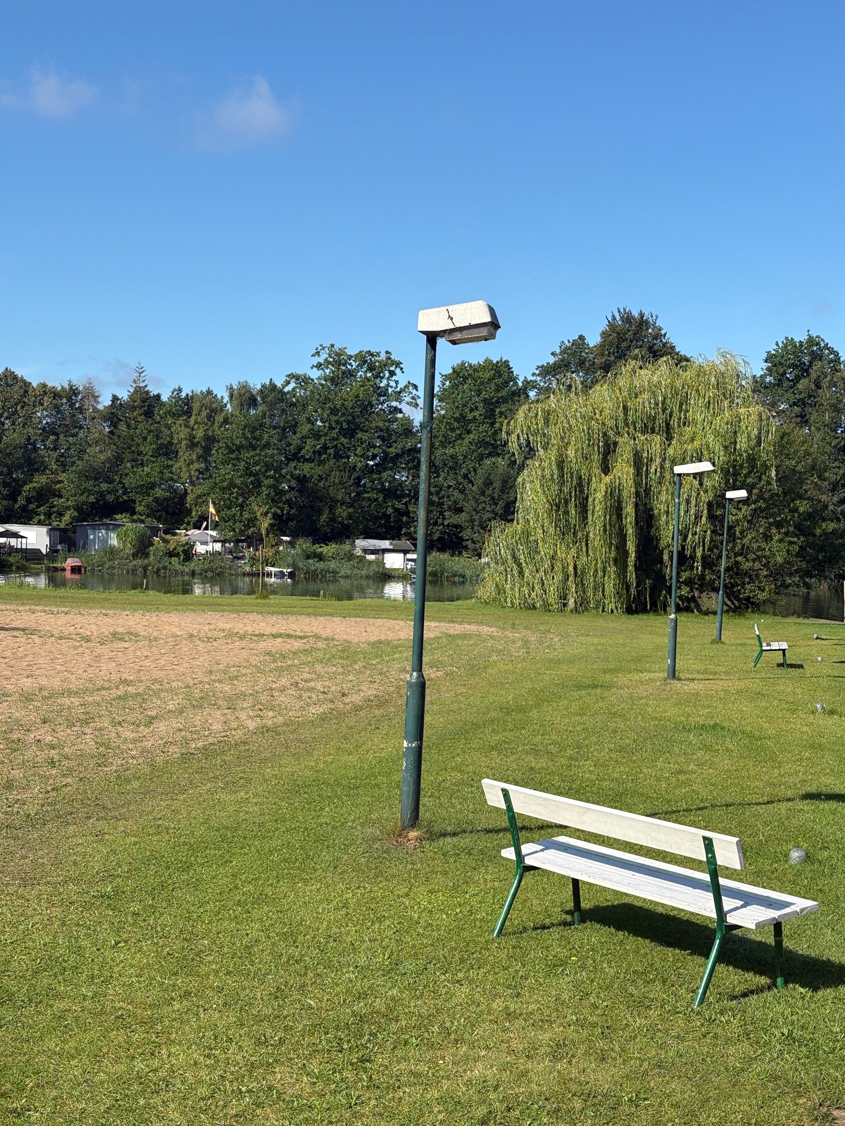A park with a bench, a lamppost, and a weeping willow tree.
