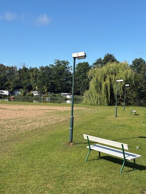 Un parque con un banco, un farol y un sauce llor ón.
