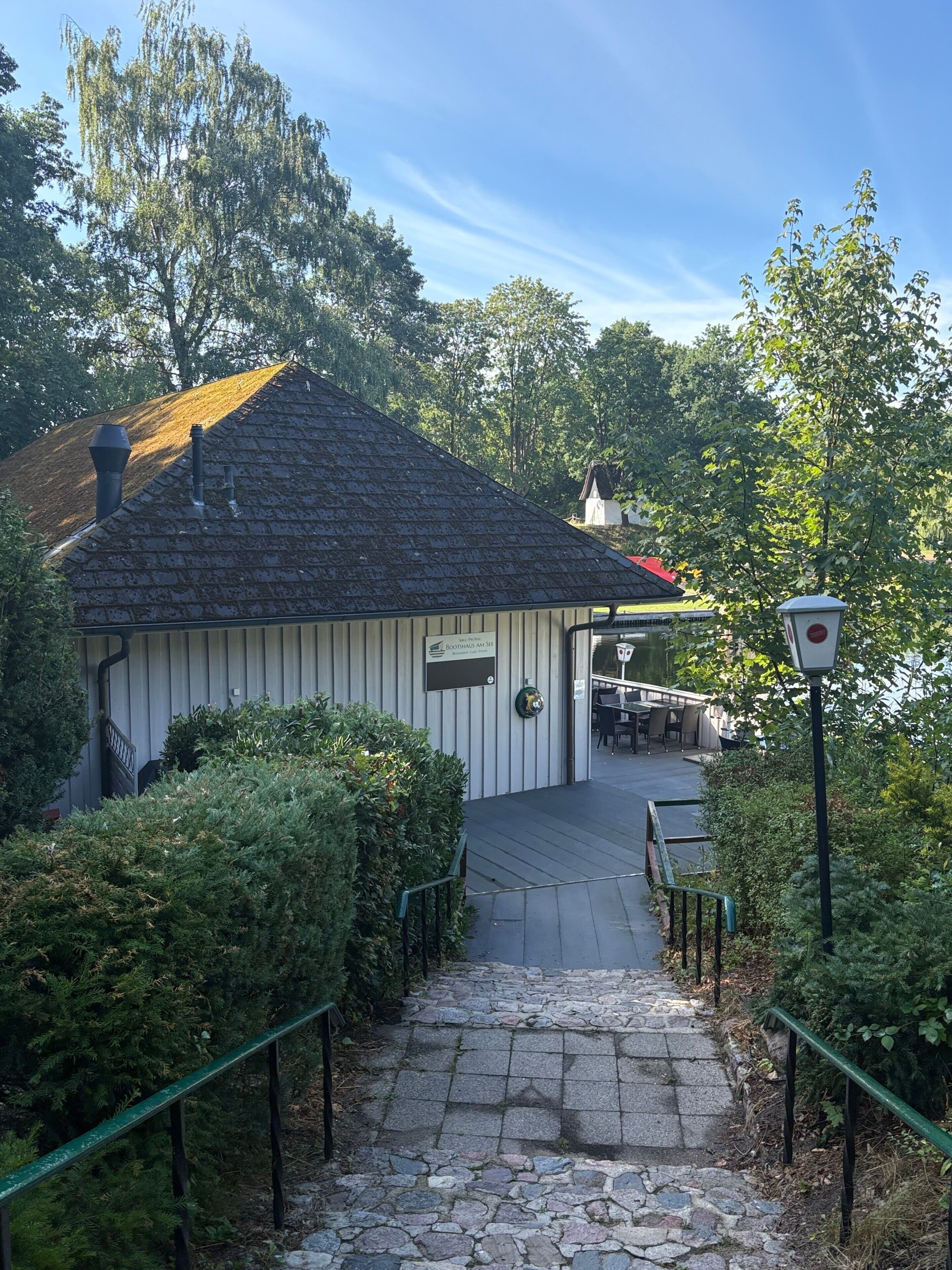 En bygning med en stentrappe, der fører til et overdækket område med borde og stole.