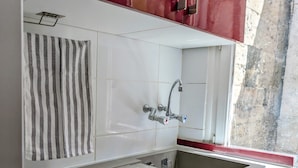 Een compacte keuken met een ingebouwde wasmachine, een spoelbak en een gestreepte handdoek.
