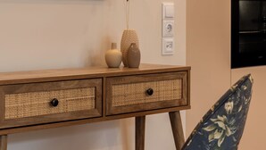 A room with a painting of a woman by a window, a desk with two drawers, a vase, and a chair with a floral pattern. - Vida Zisella | Lux Home 7' from Airport (Koropi)