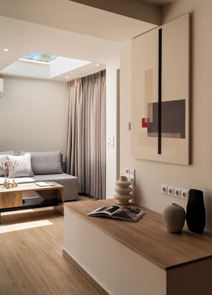 Un salon moderne avec un canapé, une table basse, un coin lecture avec un livre, un vase et un tableau accroché au mur.