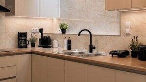 A modern kitchen with a marble backsplash, a black faucet, and various appliances. - Vida Zisella | Lux Home 7' from Airport (Koropi)