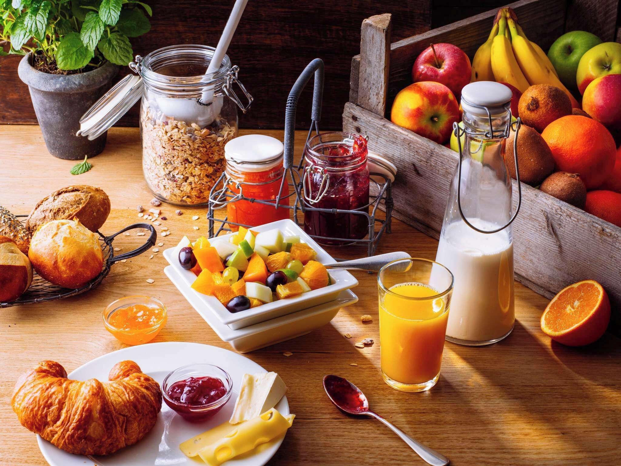 Une table mise pour le petit-déjeuner avec des fruits, du pain et des boissons.
