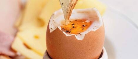 A breakfast dish with a poached egg in a cup, accompanied by toast and a side of fruit.
