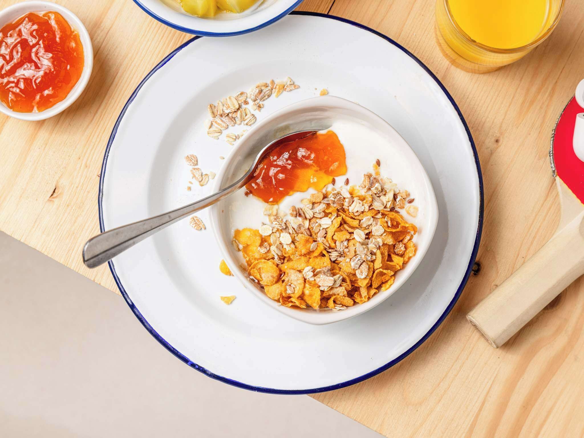 Eine Schüssel mit Müsli, Milch und Granola auf einem Teller.