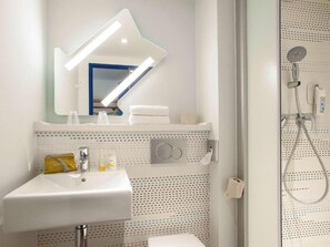 A modern bathroom with a white sink, a mirror, a shower, and a towel rack. - Ibis Budget Reims Thillois (Thillois)