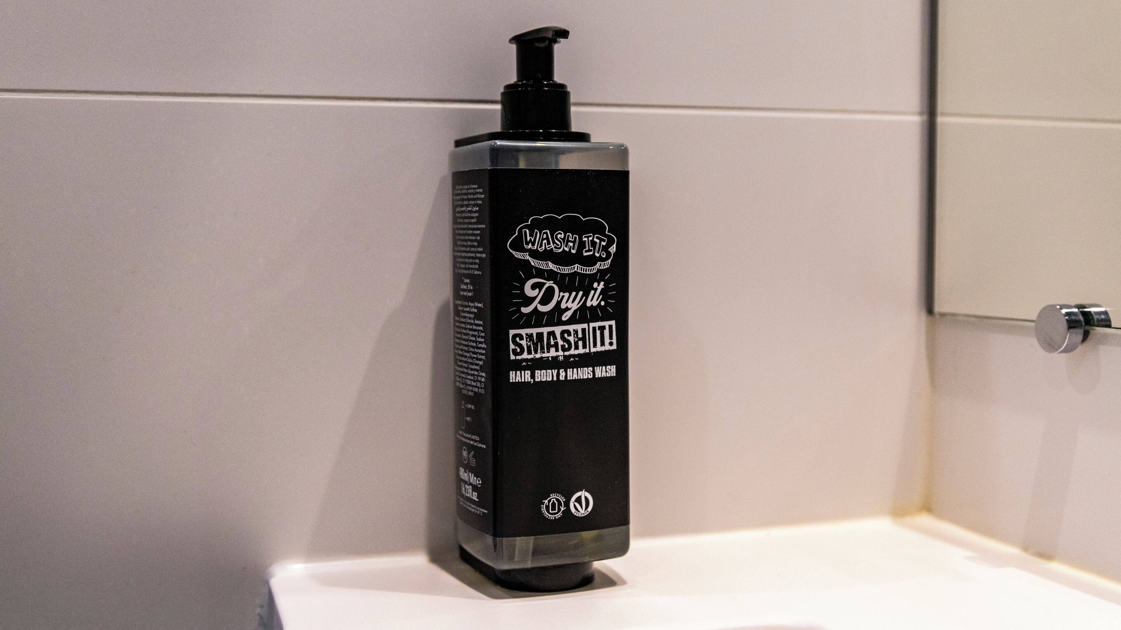 Botella negra con dosificador de bomba sobre una superficie blanca, probablemente un lavamanos de baño.