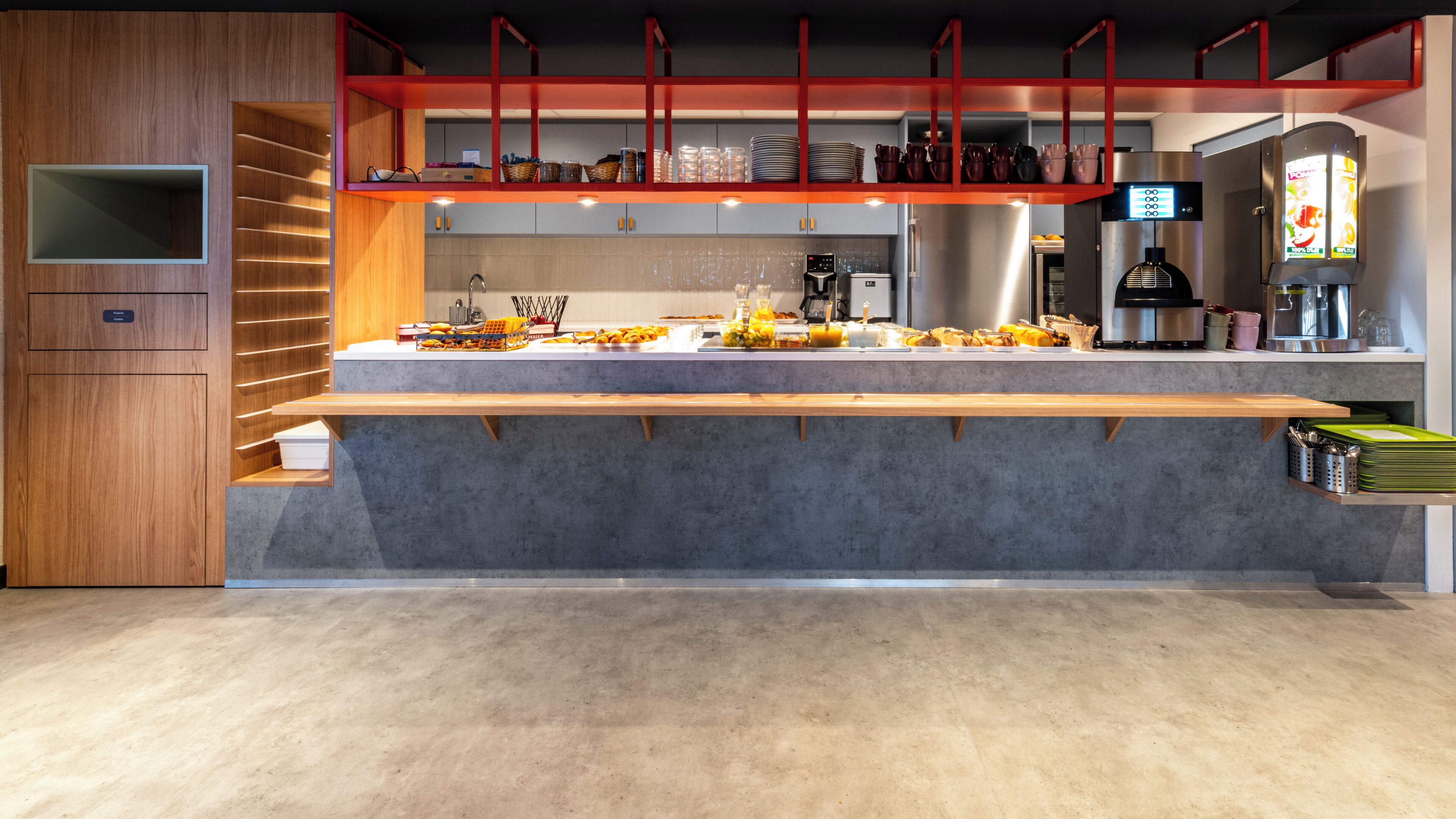 A modern kitchen with a long counter, built-in appliances, and a red accent wall.
