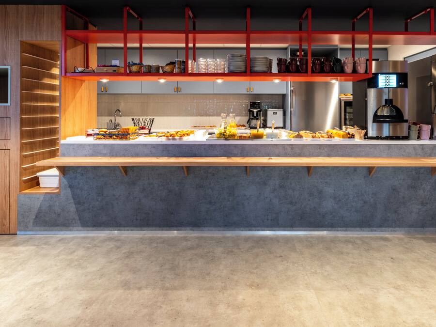 A modern kitchen with a long counter, built-in appliances, and a red accent wall.