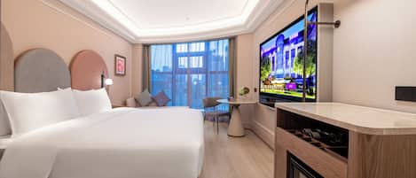 Una habitación de hotel moderna con una cama grande, un escritorio pequeño, televisión y vistas a la ciudad.