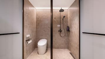 Un baño moderno con inodoro, ducha y dispensador de papel higiénico.