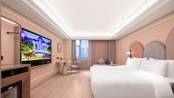 Habitación de hotel con una cama grande, televisión en la pared, una mesita y una silla.