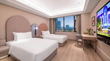 Habitación de hotel con dos camas, un escritorio, una silla, un televisor y vistas a la ciudad.