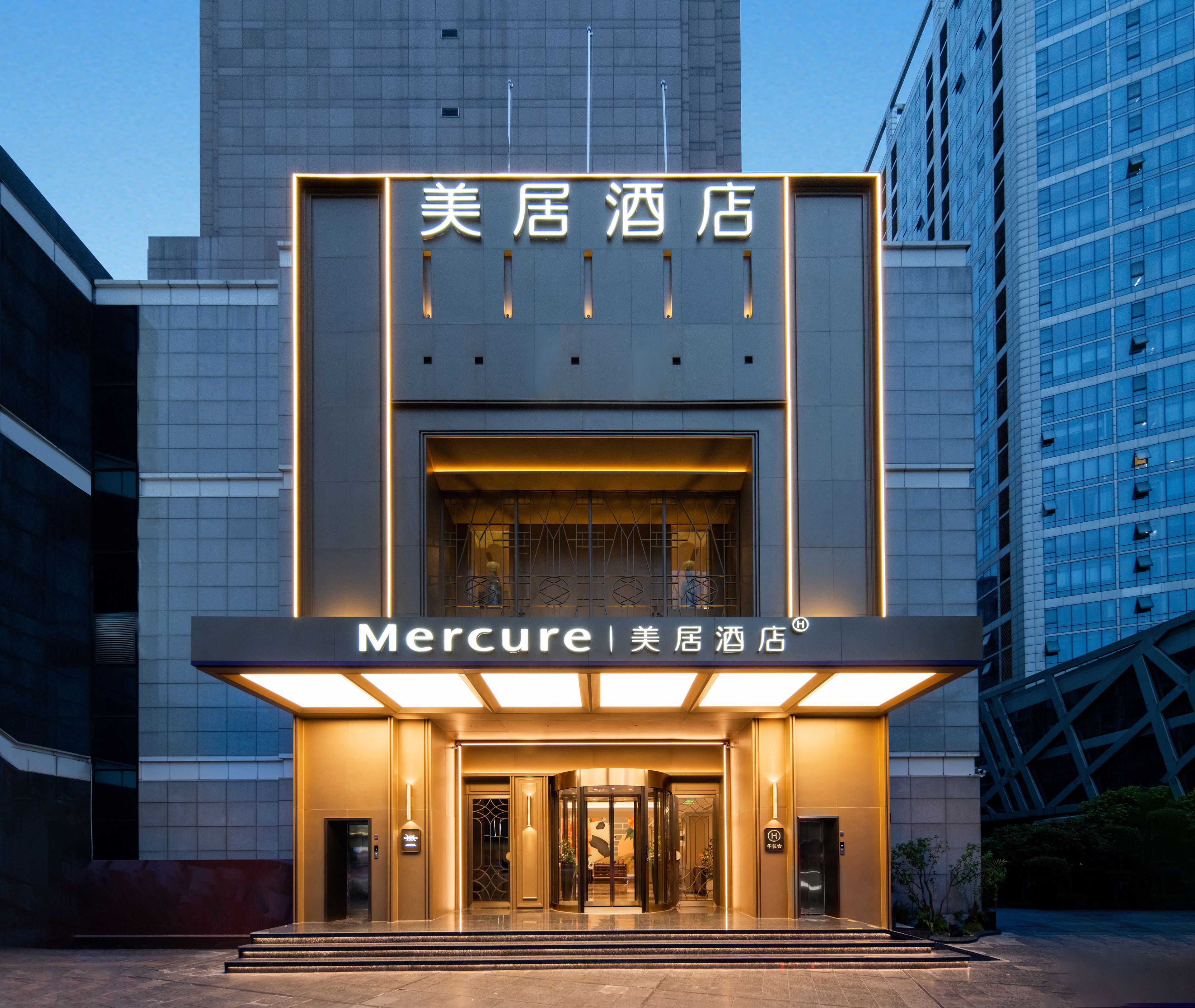 Entrada d'un hotel modern amb una porta giratòria i un rètol que diu 'Mercure'.