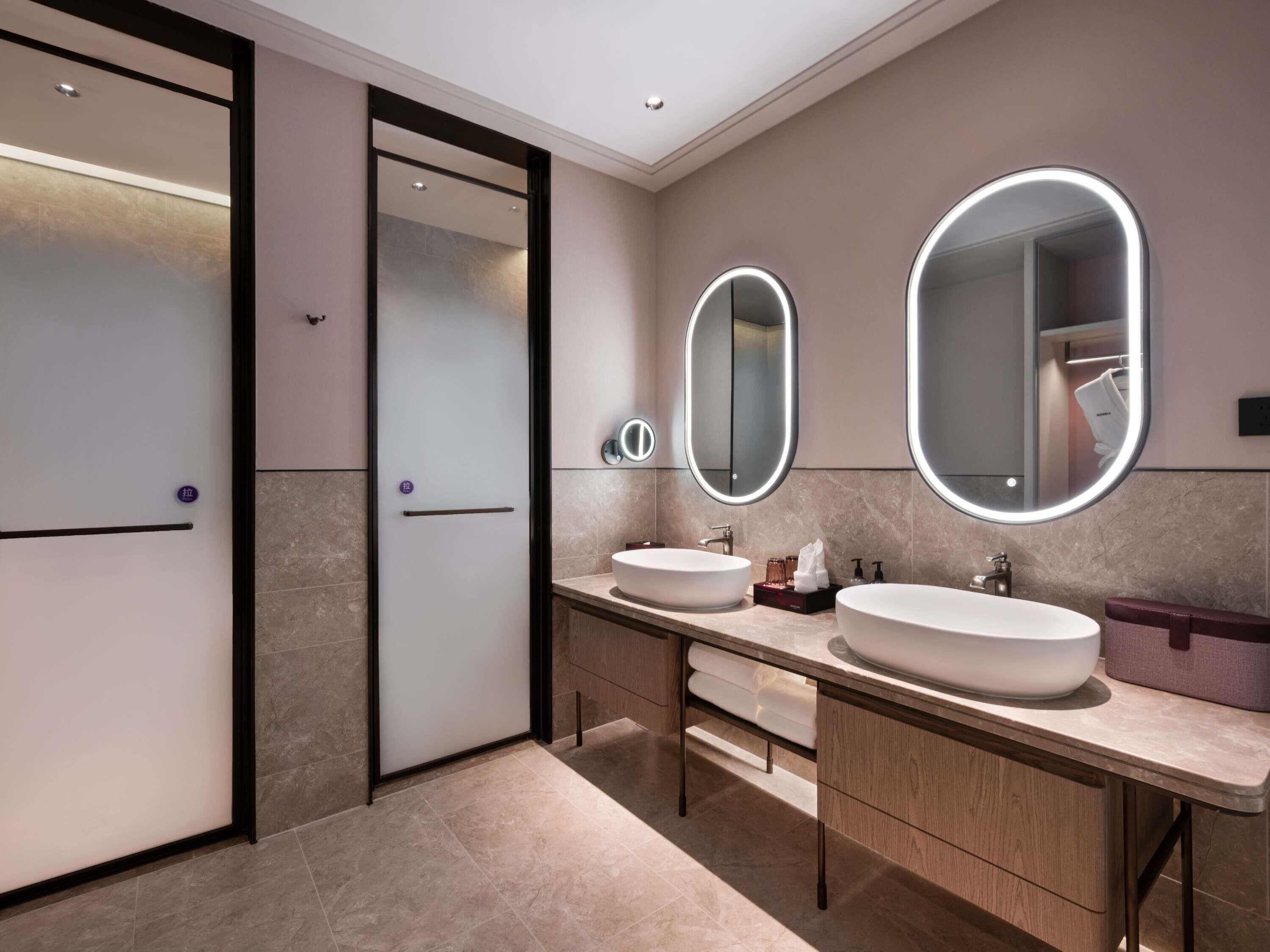 Un baño moderno con dos lavamanos, un espejo grande y un vestidor.