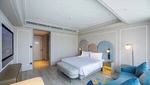 Ett modernt hotellrum med en stor säng, en sittgrupp med en blå soffa, en platt-TV och ett skrivbord.