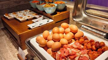 Una barra de desayuno con distintos alimentos como huevos, carnes y verduras.